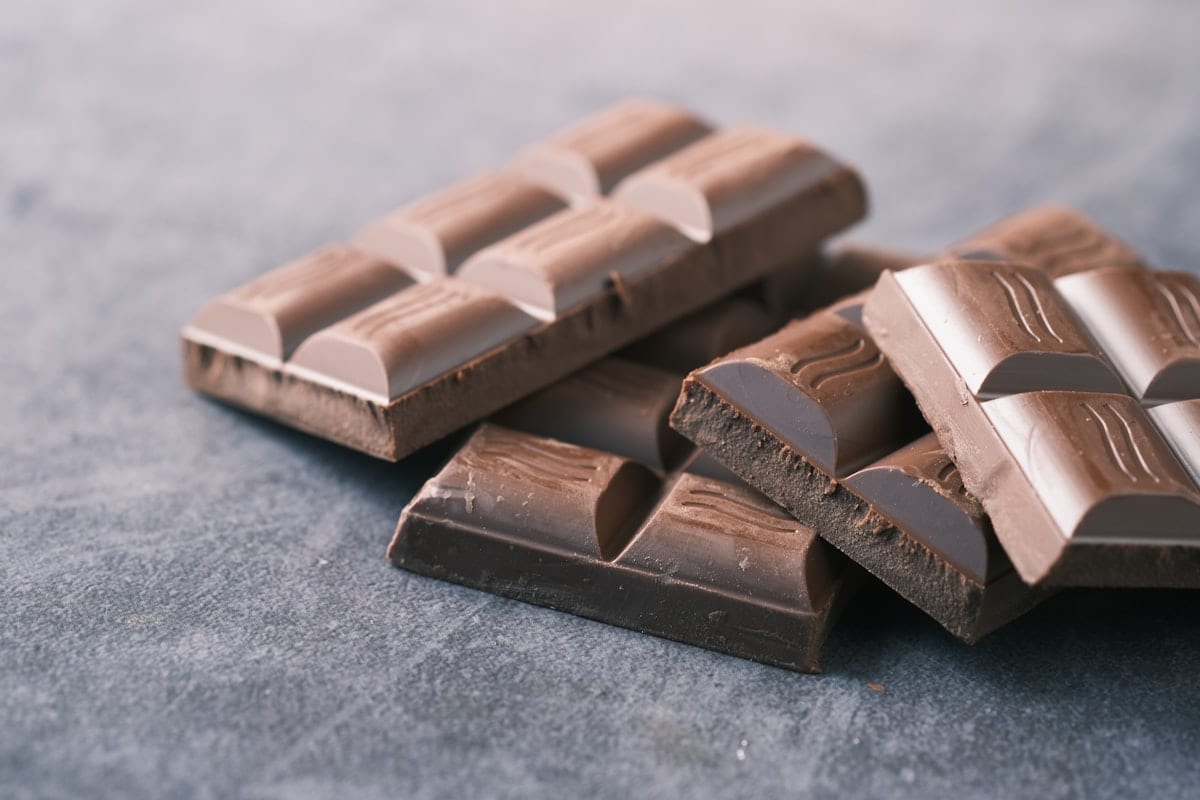 A bar of dark chocolate broken into squares on a dark surface