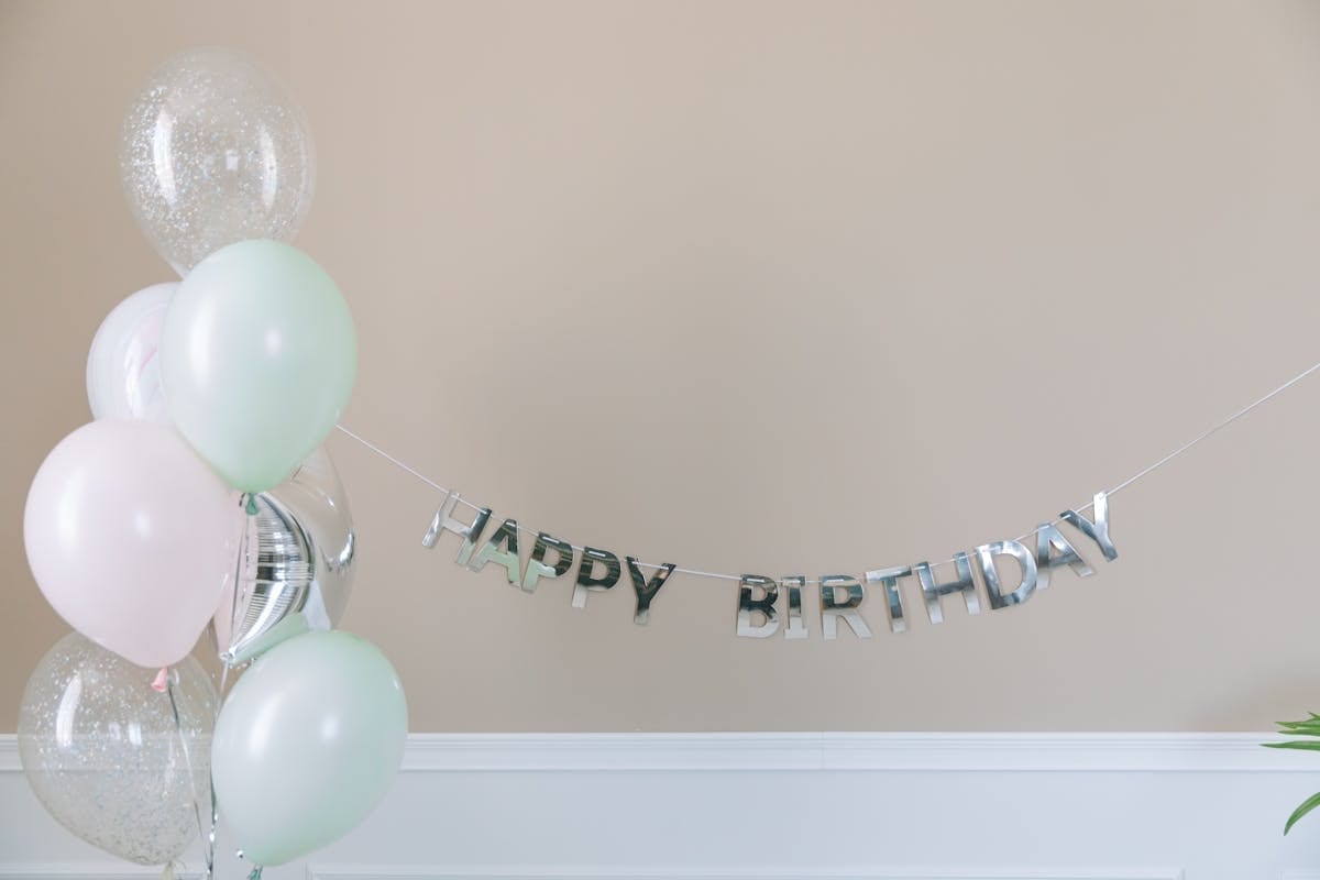 Colorful dog birthday party banner with paw prints hanging on a white wall as party backdrop
