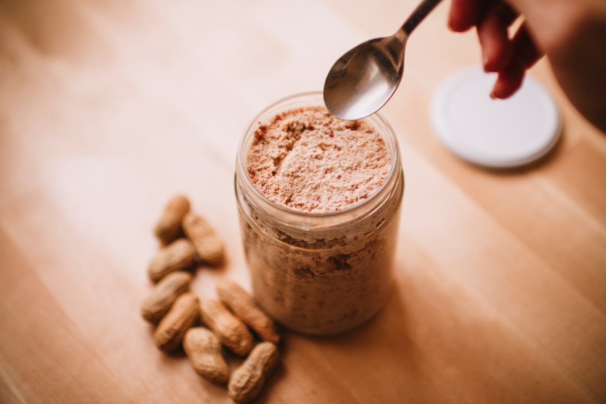Jar of homemade organic peanut butter on a wooden board